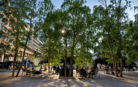 Photo for London, UK - June 14 2023:  Exchange Square at Broadgate, an open space in the City of London. People sit in the square and evening sunlight filters through the trees. Liverpool Street Station behind. - Royalty Free Image