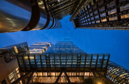 Téléchargez les photos : Londres, Royaume-Uni : En regardant le Leadenhall Building ou Cheesegrater au 122 Leadenhall Street dans la ville de Londres la nuit. Avec 8 Bishopsgate (L), le Gherkin (R) et le Lloyds Building (haut). - en image libre de droit