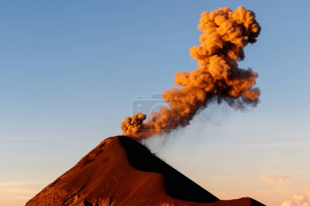 Nahaufnahme eines Vulkanausbruchs mit orangefarbener Rauchsäule bei Sonnenaufgang, klarer Tag in der Nähe von Antigua, Guatemala, Mittelamerika.