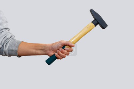 Woman's hand holdin a hammer on an isolated white background. Showing woman empowerment and equality.