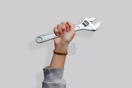 Woman's hand holding a wrench on an isolated white background. Showing woman empowerment