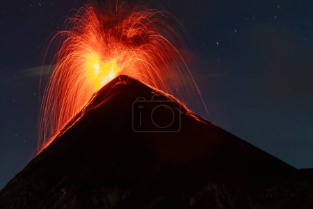 Volcano fuego erupting with a fire explosion of orange lava or magma at night with long exposure in guatemala seen from acatenango.