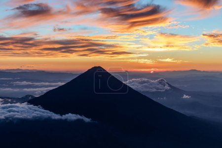 Silhouette des Vulkans de agua bei glühend orangefarbenem Sonnenaufgang oder Sonnenuntergang von der Spitze des Vulkans de acatenango, Guatemala