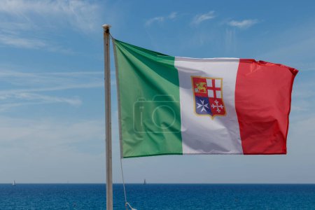 Flagge der italienischen Marine Marina Militare vor blauem Himmel mit Ozean am Horizont.