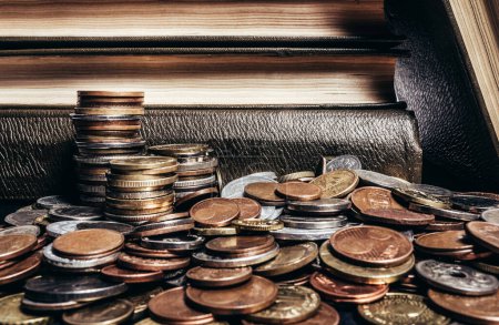 Foto de Foto de viejos libros antiguos marrones apilados en una pila de monedas del mundo. - Imagen libre de derechos