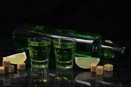 Téléchargez les photos : Boisson absinthe verte sur fond noir avec sucre et citron vert - en image libre de droit