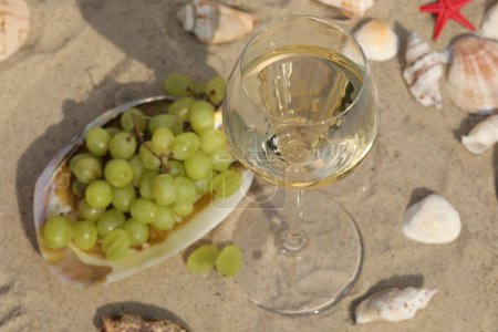Téléchargez les photos : Verre de vin blanc sur sable comme fond avec coquilles - en image libre de droit