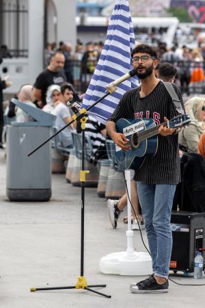 Photo for Istanbul, Turkey - June 20, 2023: Street musician playing acoustic guitar in the street. People listening - Royalty Free Image