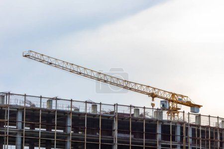 Téléchargez les photos : Grue de chantier et bâtiment en construction contre ciel nuageux - en image libre de droit