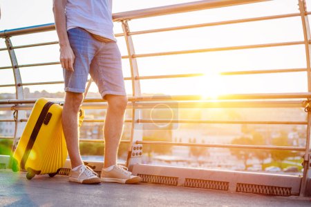Téléchargez les photos : Voyage homme marche avec valise jaune marche à travers la ville - en image libre de droit