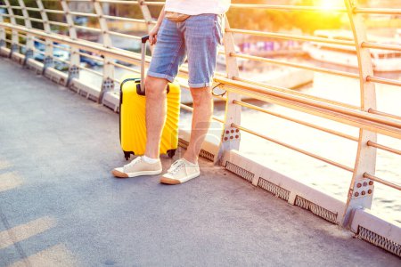 Foto de Hombre de viaje caminando con maleta amarilla caminando por la ciudad - Imagen libre de derechos
