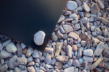 Photo for Yoga mat on a sandy pebble beach. Healthy lifestyle, harmony concept - Royalty Free Image
