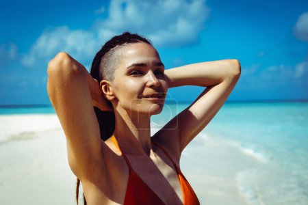 Téléchargez les photos : Belle dreadlocks femme relaxante sur la plage. Brunette bronzée fille en maillot de bain profiter des vacances - en image libre de droit