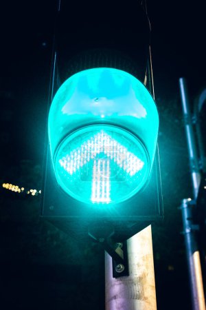 Photo for Green glowing arrow. Night traffic light.Go straight upwards - Royalty Free Image