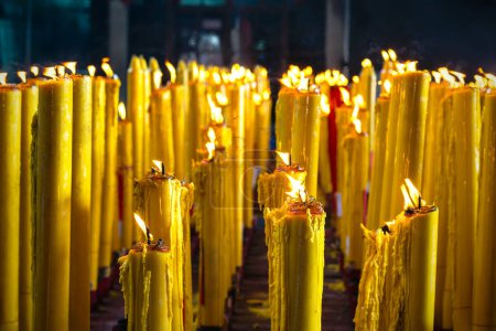 Téléchargez les photos : Bougies allumées qui brûlent dans le noir. Prières cire bougies dans le temple bhoutdiste - en image libre de droit