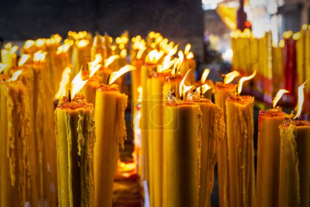 Photo for Lit Candles burning in the dark. Prayers wax candles in Bhuddist Temple - Royalty Free Image