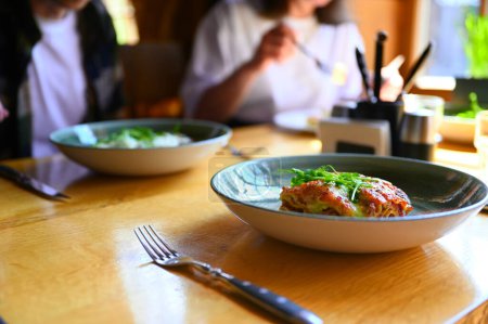 Foto de Una deliciosa porción de lasaña en un restaurante, listo para saborear. Las capas de pasta, queso y salsa son visualmente atractivas, y el aroma es deliciosa - Imagen libre de derechos