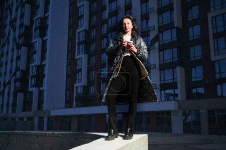 Photo for A happy woman holding keys to her new flat in an urban setting, with a big smile on her face. She appears excited and optimistic about the new chapter in her life. - Royalty Free Image