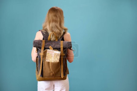 Téléchargez les photos : Jeune jolie hipster femelle avec sac à dos vintage isolé sur fond. Étudiante séduisante en lunettes, haut court noir et pantalon blanc. Femme souriante montrant des expressions. Voyage avec sac à dos - en image libre de droit