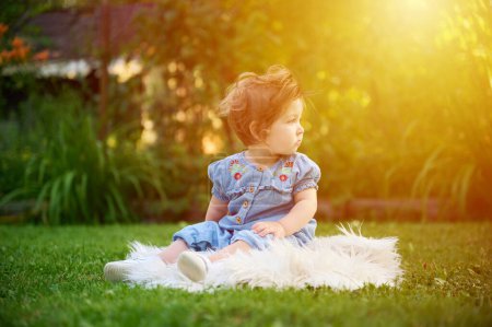 Téléchargez les photos : Adorable fille sur l'herbe dans le jardin. Gros plan portrait. Bonne petite fille dans les paysages d'été. Doux petit enfant à l'extérieur. - en image libre de droit