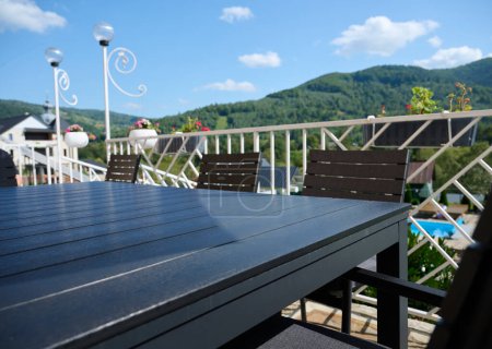 Photo for Wide angle, view of the terrace with a table and an umbrella from the sun. Apartment for rest in the mountains. Resort in Carpathian mountains. - Royalty Free Image