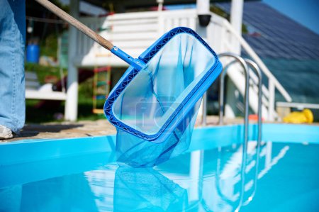 Photo for Close up view of scoop net over the swimming pool. Worker cleaning water by skimmer. Cleaning outdoor pool by net. - Royalty Free Image