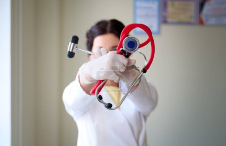 Photo for Portrait of young female neurologist with hammer and stethoscope in doctor's hands - Royalty Free Image