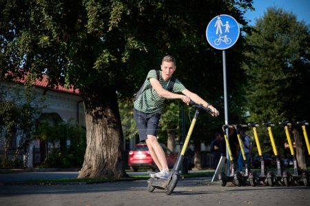 Téléchargez les photos : Jeune homme en scooter électrique dans le parc
. - en image libre de droit