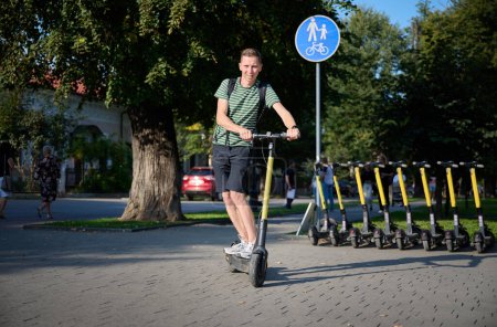Téléchargez les photos : Jeune homme en scooter électrique dans le parc
. - en image libre de droit