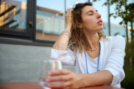 Foto de Retrato de una joven atractiva mujer de negocios sentada en una mesa en un café y sosteniendo un vaso de agua transparente. Vista de cerca. - Imagen libre de derechos