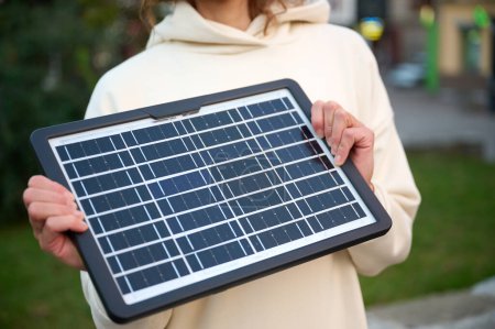 Photo for Top view of woman holding portable solar panel with reflected sunlight. Close up view of woman hands charging her devices with portable solar panel. Alternative energy. Renewable energy concept. - Royalty Free Image