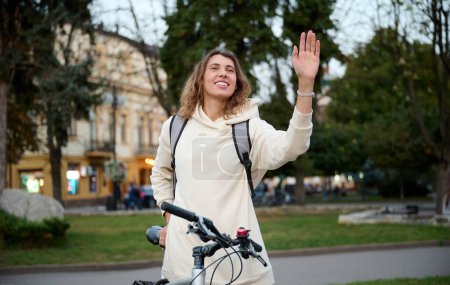 Téléchargez les photos : Gros plan portrait de femme avec sac à dos et vélo marchant à travers la ville et le long du remblai le soir au coucher du soleil. - en image libre de droit