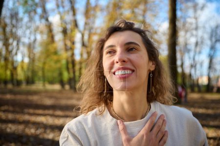 Foto de Retrato de una joven sonriente en un parque de otoño en un día soleado brillante. Vista de cerca. Tiempo de otoño. - Imagen libre de derechos