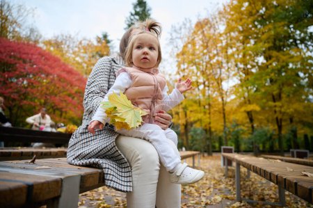 Téléchargez les photos : Mère et jolie petite fille marchant dans le parc d'automne avec des feuilles sur le sol. Maman passe du temps avec un petit enfant dans le parc. ? l'acceptation d'une bonne relation mère-enfant. - en image libre de droit