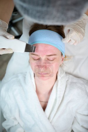 Téléchargez les photos : Vue rapprochée du nettoyage de la peau et de la procédure de peeling du visage en clinique de beauté. Traitement de nettoyage des pores en profondeur - en image libre de droit