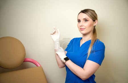 Foto de Bastante ginecóloga doctora en guantes estériles médicos azules preparándose para el examen vaginal. Salud de la mujer. Enfermedad preventiva. Detección temprana de cáncer. Revisa. - Imagen libre de derechos