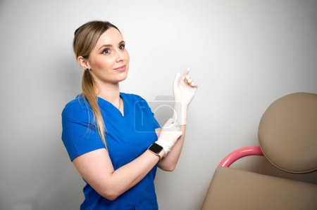 Foto de Bastante ginecóloga doctora en guantes estériles médicos azules preparándose para el examen vaginal. Salud de la mujer. Enfermedad preventiva. Detección temprana de cáncer. Revisa. - Imagen libre de derechos