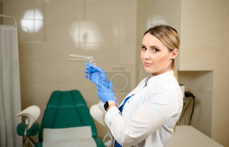 Hübsche Ärztin Gynäkologin in blauen sterilen medizinischen Handschuhen mit vaginalem Spekulum. Frauengesundheit. Prävention von Krankheiten. Krebsfrüherkennung. Untersuchung und Beratung des Patienten in der Klinik.