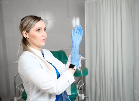 Jolie femme médecin gynécologue en gants stériles médicaux bleus se préparant à l'examen vaginal. La santé des femmes. Prévention des maladies. Détection précoce du cancer. Vérifiez.