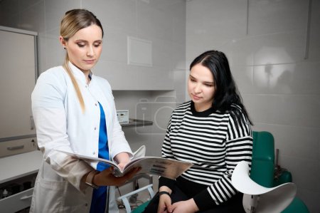 Pretty female doctor gynecologist consulting pregnant woman. Examining and consulting young pregnant woman patient in clinic.Obstetrical examination. Baby and mother healthcare check up.Women's health