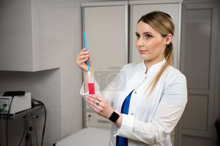 Pretty female doctor gynecologist holding test tube for vaginal examination. Women's health. Prevention illness. Early detection of cancer. Examining and consulting patient in clinic.