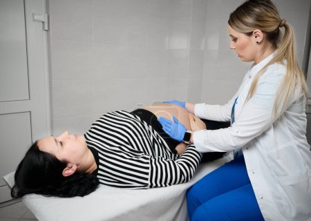 Photo for Pretty female doctor gynecologist consulting pregnant woman. Examining and consulting young pregnant woman patient in clinic.Obstetrical examination. Baby and mother healthcare check up.Women's health - Royalty Free Image