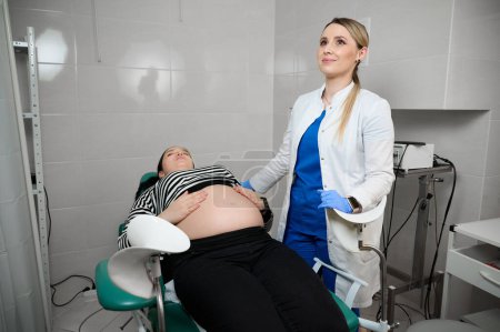 Photo for Pretty female doctor gynecologist consulting pregnant woman. Examining and consulting young pregnant woman patient in clinic.Obstetrical examination. Baby and mother healthcare check up.Women's health - Royalty Free Image