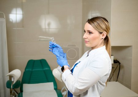 Foto de Linda ginecóloga doctora en guantes estériles médicos azules sosteniendo espéculo vaginal. Salud de la mujer. Enfermedad preventiva. Detección temprana de cáncer. Examinar y consultar al paciente en la clínica. - Imagen libre de derechos