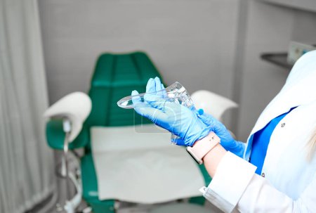 Photo for Pretty female doctor gynecologist in blue medical sterile gloves holding vaginal speculum. Women's health. Prevention illness. Early detection of cancer. Close up - Royalty Free Image