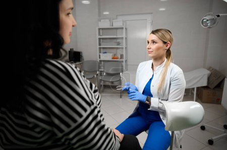 Jolie femme médecin gynécologue en gants stériles médicaux bleus tenant spéculum vaginal. Examen obstétrical. Le bilan de santé de bébé et mère. Santé des femmes.
