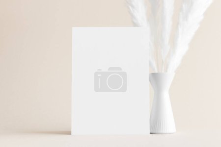 White invitation card mockup with a pampas decoration on the soft yellow background. 5x7 ratio, similar to A6, A5.