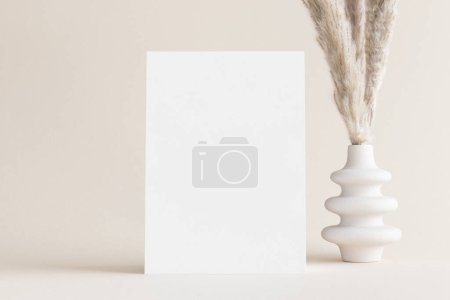 Photo for White invitation card mockup with a pampas decoration on the soft yellow background. 5x7 ratio, similar to A6, A5. - Royalty Free Image
