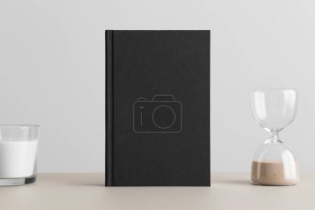 Black book mockup with a candle on the beige table.