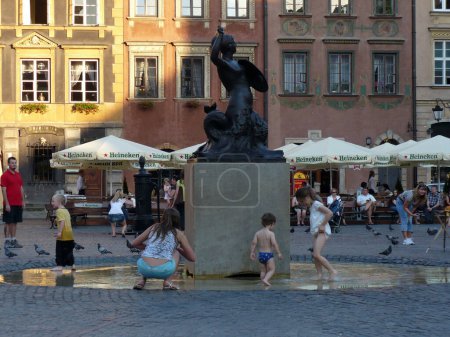 Téléchargez les photos : Fontaine de statue de sirène place de la vieille ville dans les enfants du milieu jouant sur la place du marché - en image libre de droit